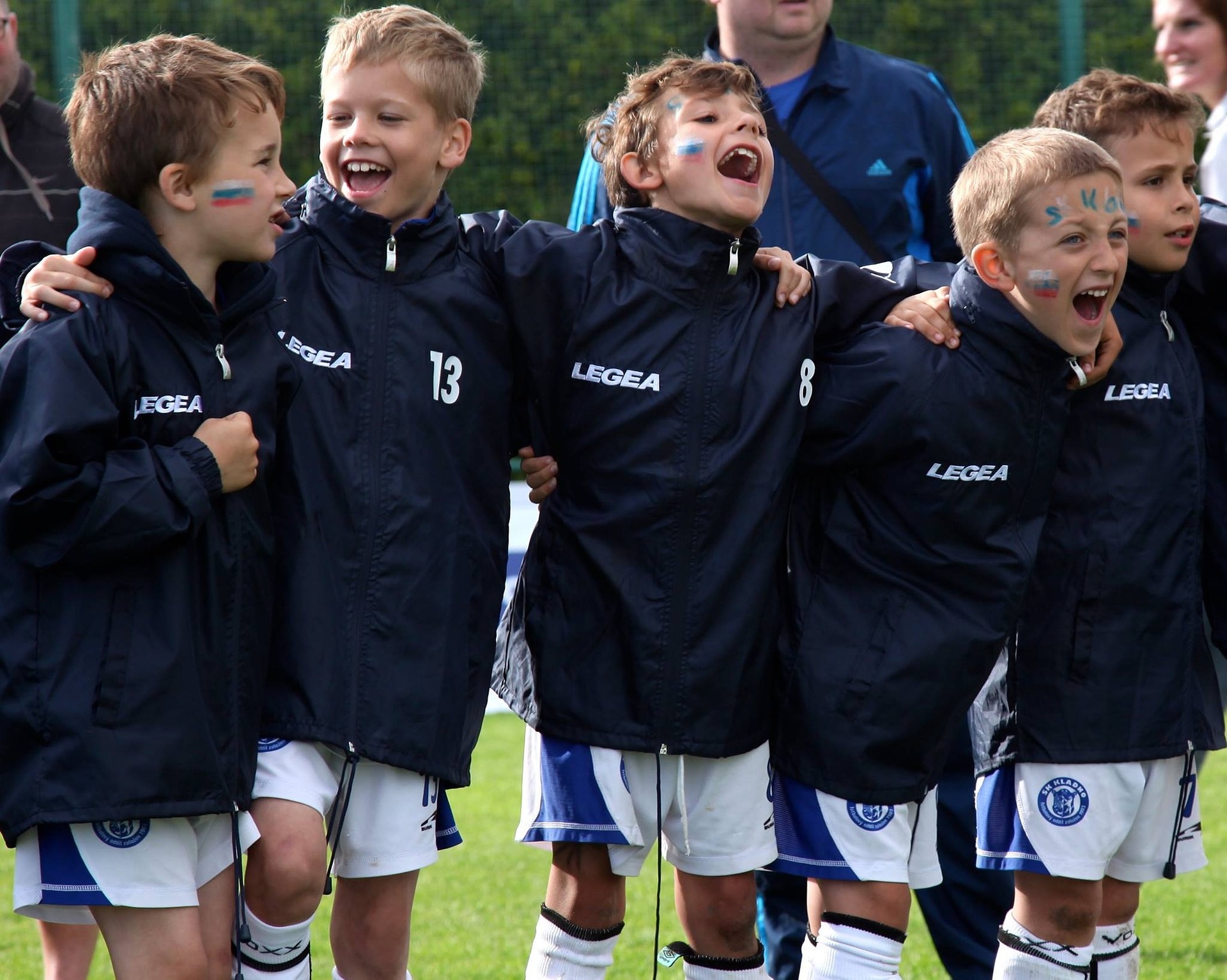 A group of young soccer players celebrating together with arms around each other after making the team