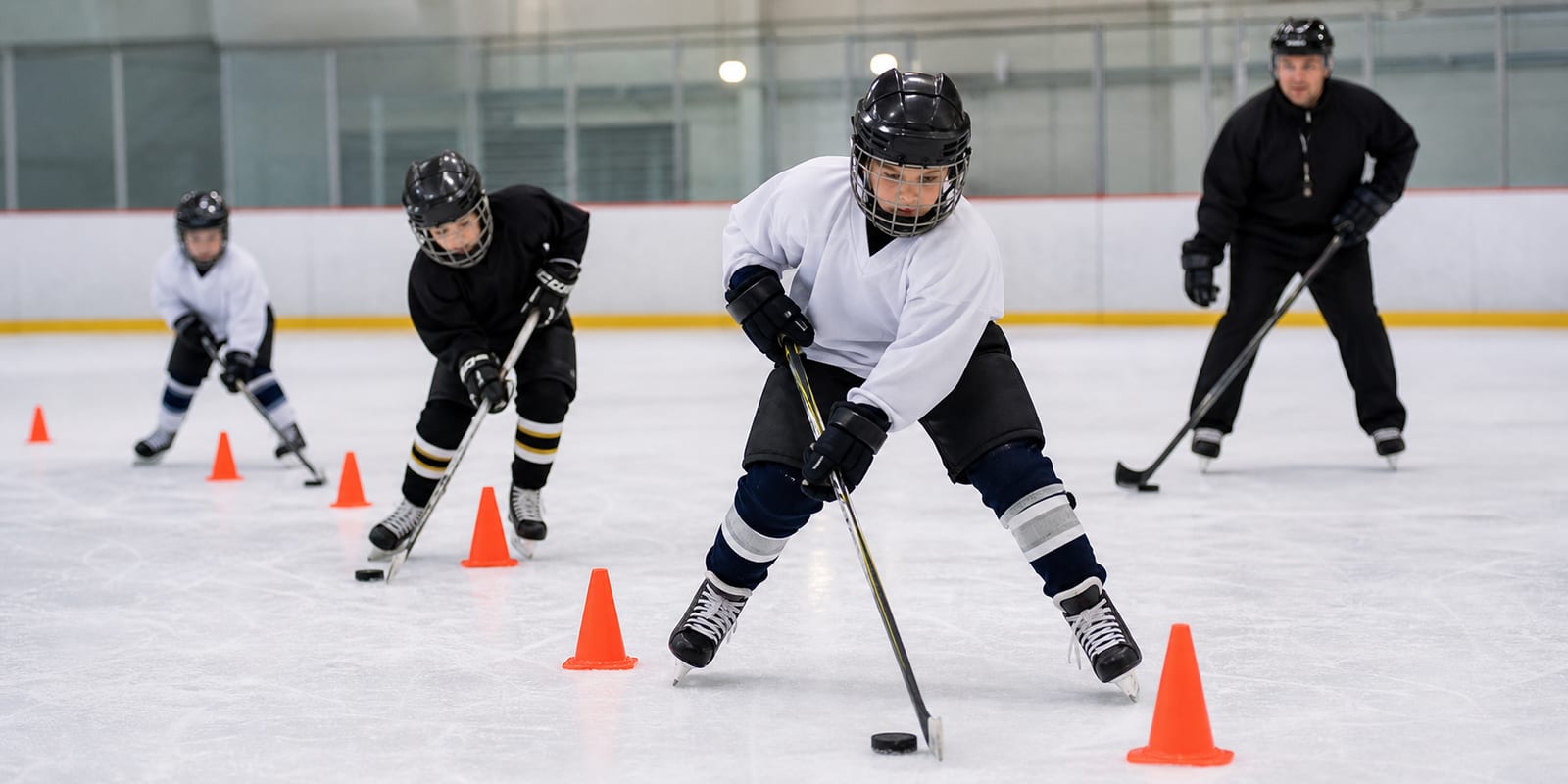 Youth hockey players practicing angling and body positioning drills along the boards