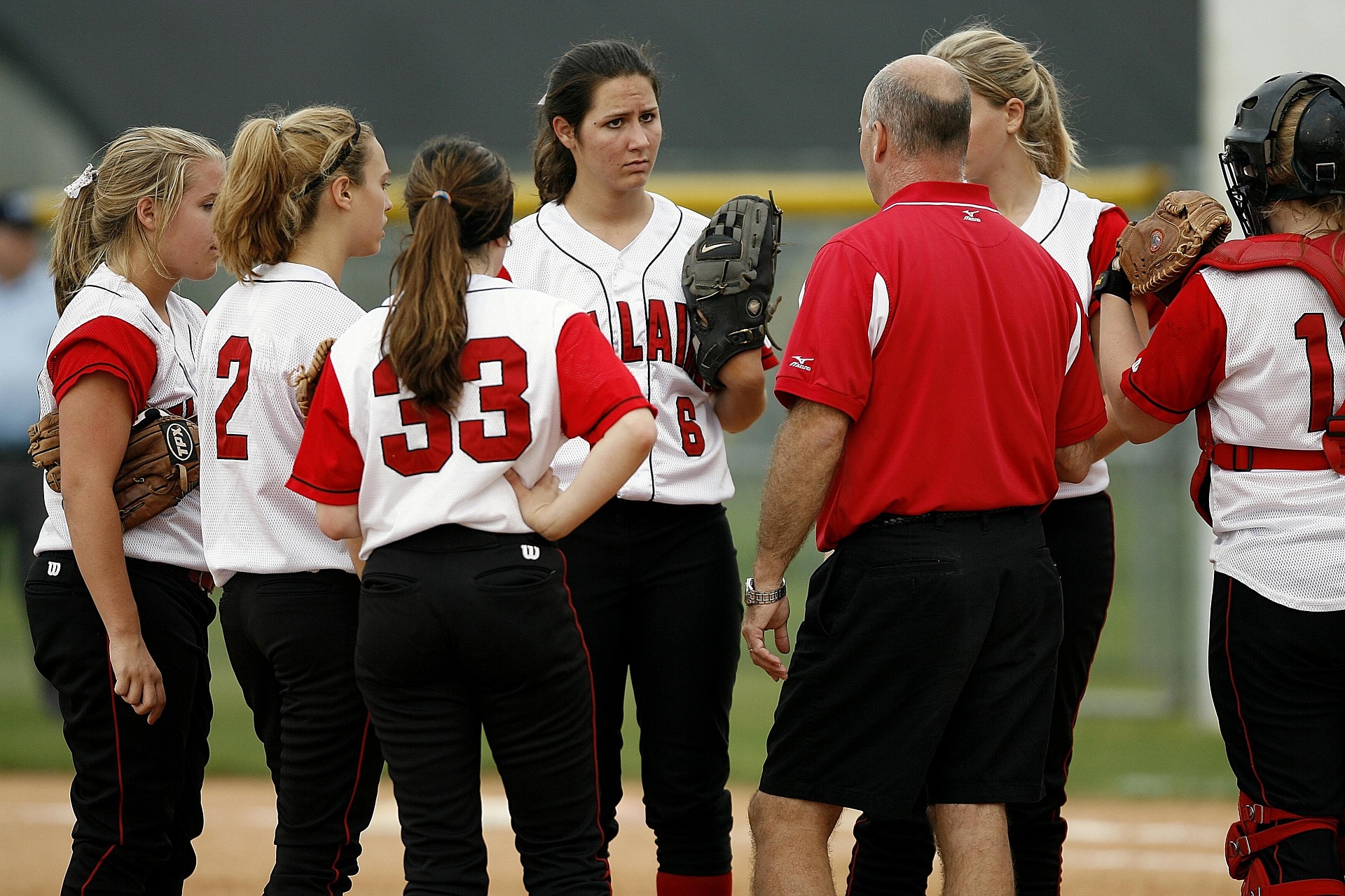 Coach supporting youth softball players during practice
